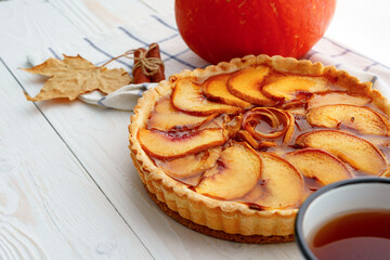 Apple tart pie on table with pumpkin and dry leaves