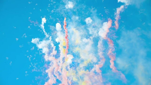 Multicolored fireworks exploding in the bright clear blue sky in the daytime