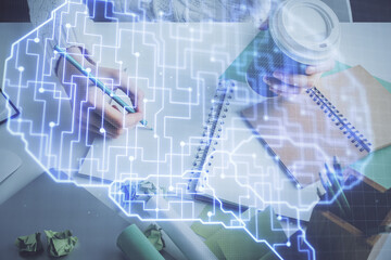 Multi exposure of writing hand on background with brain hologram. Concept of self learning.