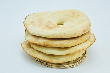 Fresh round pita bread on a clean white background. Flat unleavened white bread baked in a tandoor. Ready-made fresh pastries in the middle lies on a wicker tray.