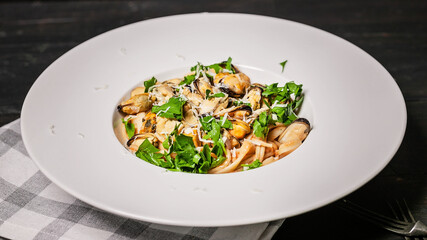 Pasta with mussel meat, herbs and cheese. Traditional seafood with fresh parsley on a white plate. Food banner format
