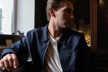 portrait of a young man sitting at the table. man in a jacket and a T-shirt