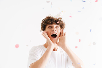 Young curly joyful guy with party cone laughing and having fun