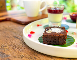Chocolate brownie topped with almonds Placed on a white plate on a wooden table.