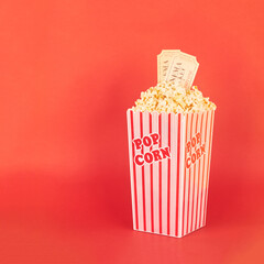 popcorn in red and white bucket with cinema tickets in red background