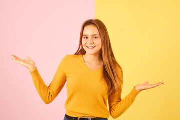 young lady choosing options Concept of  balance on a pink and yellow background