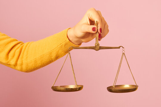 woman hand holding a balance on pink background