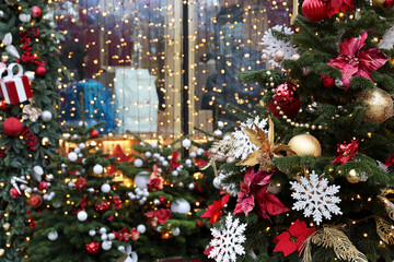 Christmas decorations in a shop window on a city street. Fir branches, toy balls and festive lights, New Year celebration, magic of the holiday