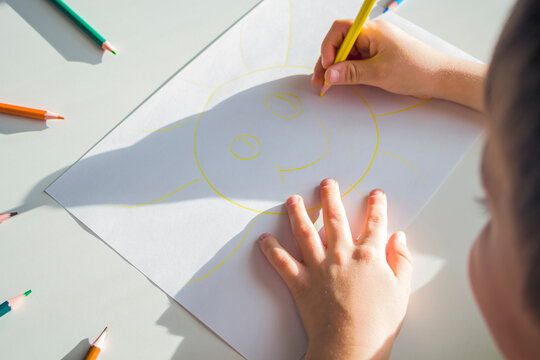 Kid draws sun with pencils. Child's creativity and art. Preschooler gets drawing skills in kindergarten. Children Protection Day