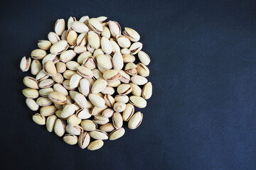 a lot of pistachio grains close-up lined in a circle top view on a black background