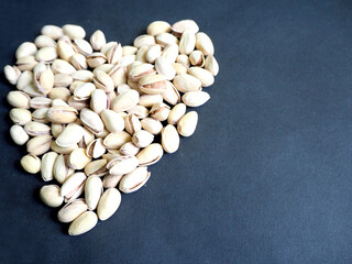 many pistachio seeds are laid out in a heart shape on a black background on the side . pistachio grain variety