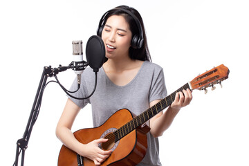 Young asian woman with microphone recording song and playing guitar in music studio, Woman performing in a recording studio for her album isolated on white background.