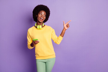 Photo of dark skin lady hold cellphone point finger copyspace wear jumper trousers isolated on violet color background