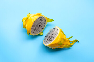 Yellow pitahaya or dragon fruit on white plate on blue background.