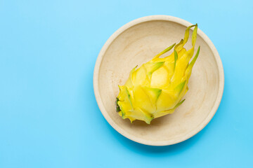 Yellow pitahaya or dragon fruit on plate on blue background.