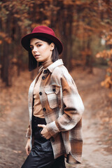 Beautiful elegant woman standing in a park in autumn
