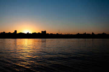 sunset over the city, the sun sets over the horizon, clear sky, in the foreground of the river, use as a background or text
