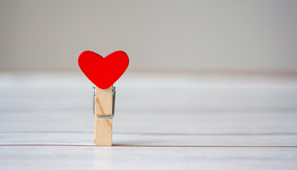Clothes pin with a red heart as a concept of loneliness in the 21st century. Looking for love or...