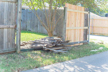 Aged wooden fence near new lumber boards installation of suburban residential house in Texas, USA