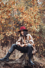 Young woman fashionably dressed in a dry autumn forest