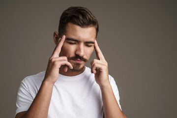 Image of unhappy unshaven guy with headache rubbing his temples