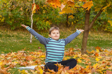 Children play in the autumn Park. The kids throw yellow leaves. Baby boy with a maple leaf. Autumn foliage.