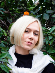 Girl with blond hair in a tangerine garden