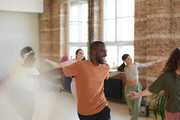 Excited African man dancing together with other young people in dance studio