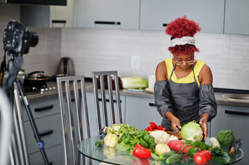 African american woman filming her blog broadcast about healthy food at home kitchen. She cuts the cabbage.