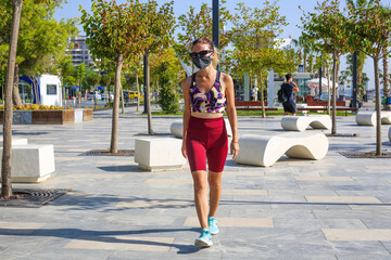 Young woman making morning exercise and wearing cloth face mask at the park in Antalya Turkey.