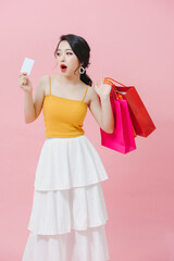 Pretty Asian woman is showing credit card in her hand along with several shopping bags in another hands