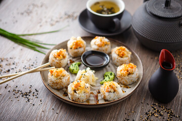 Baked sushi maki rolls with prawns and crab on a plate with chopsticks, soy sauce, wasabi and ginger. Japanese traditional fish food closeup served for lunch in modern gourmet restaurant