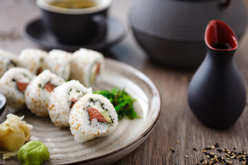 Sushi maki rolls Philadelphia with salmon, creamy cheese and avocado on a plate with chopsticks, soy sauce, wasabi and ginger. Japanese traditional seafood served for lunch in modern restaurant