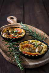 Two vegetarian tartlets on wooden board on a rustic wooden table, vertical stock photo with copy space