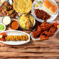 Assorted indian food on wooden background. Chicken Tikka, chicken biryani, tandoori chicken, , masala kulcha.. Dishes and appetizers of indian cuisine