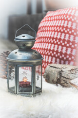 Silver lantern and a red and white Christmas pillow on a white lambskin on wooden veranda, vertical stock photo.
