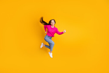 Fototapeta na wymiar Full length profile photo of pretty young girl jump wind long hairdo wear pink sweater jeans sneakers isolated yellow color background