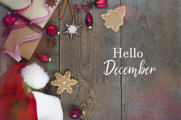 hello december - text. red santa hat, christmas tree decorations, gingerbread cookie, gift, ribbons. new year, christmas card. 