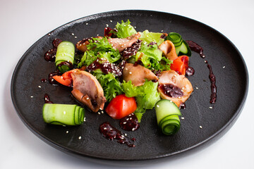 Salad with squid, tomatoes and cucumbers on a dark plate