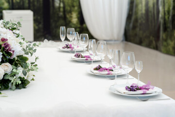 party reception table decorated with flowers: plates, forks, knives and wine glasses.