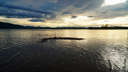 Fototapeta premium The golden sun sets in the evening with a large reservoir and mountains. 