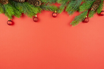 Christmas festive red decorations, fir tree branches on red background. Flat lay. Top view. Copy space. Template composition.