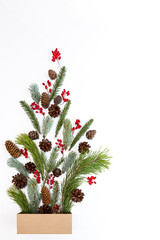 Box with various colored Christmas decorations on a white background. Festive concept. Various coniferous branches and cones, berries copy top view