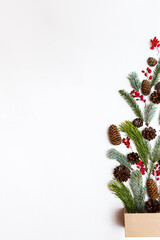 Box with various colored Christmas decorations on a white background. Festive concept. Various coniferous branches and cones, berries copy top view