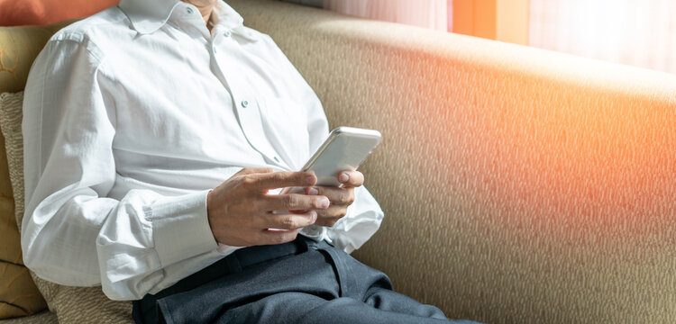 Good life and easy relax business man lifestyle after work at hotel sitting playing game using smartphone for happy businessmen people.Simplify Your Life Week..