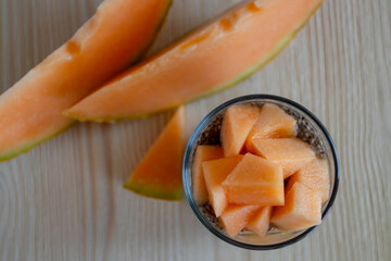 chia pudding with melon in a glass stands on a wood background