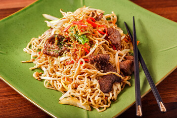 Japanese Beef Yakisoba entree with chopsticks in a green plate