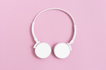 White headphones on pink paper background. Music concept. Dj Headset. Minimal style.