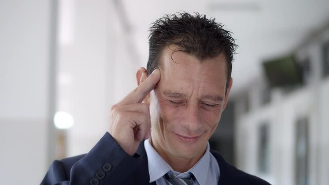 A business man wearing a suit and a tie is feeling a headache because of stress from work.