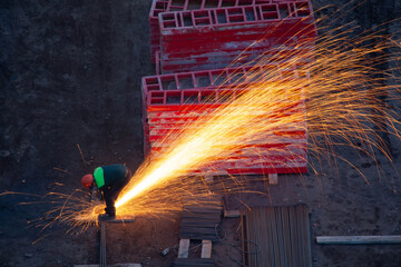 Industrial worker sawing metal with many sharp sparks